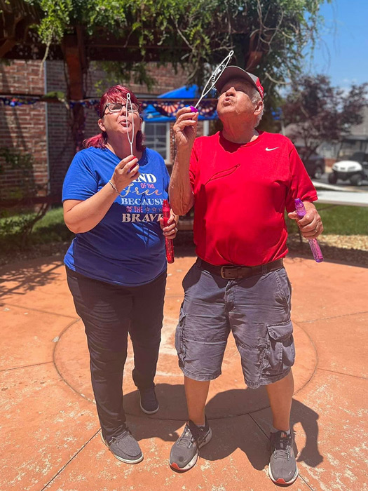 Residents enjoy a fun-filled afternoon blowing bubbles at the senior living community's courtyard event.