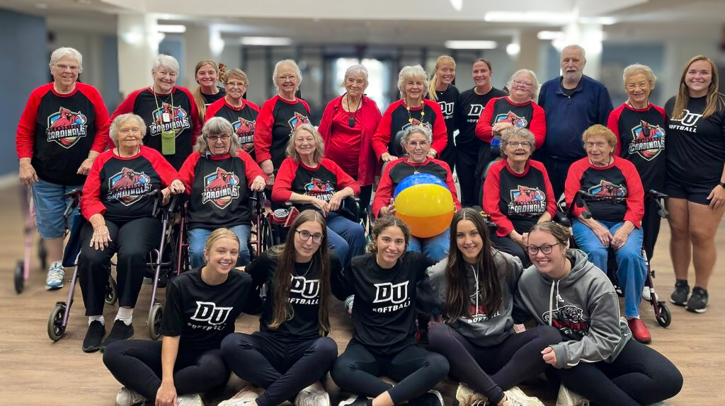 The Cambridge residents wearing team shirts pose with a visiting team, and a beach ball, to highlight chair beachball volleyball.