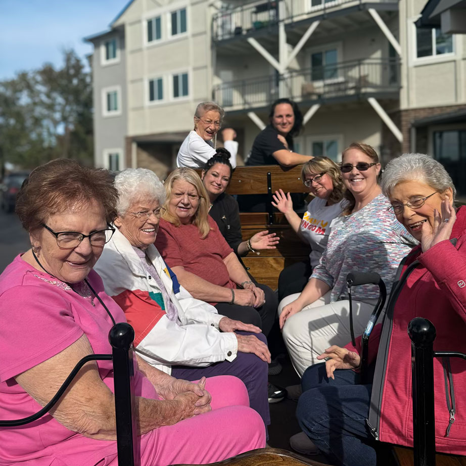 A group of senior residents and team members enjoy a carriage ride on a sunny day.