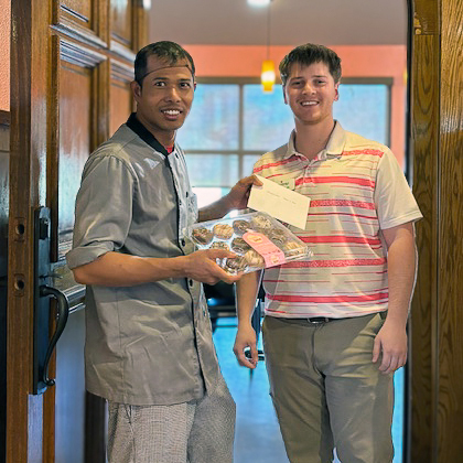 A team member smiles alongside a local business owner with a gift of appreciation.