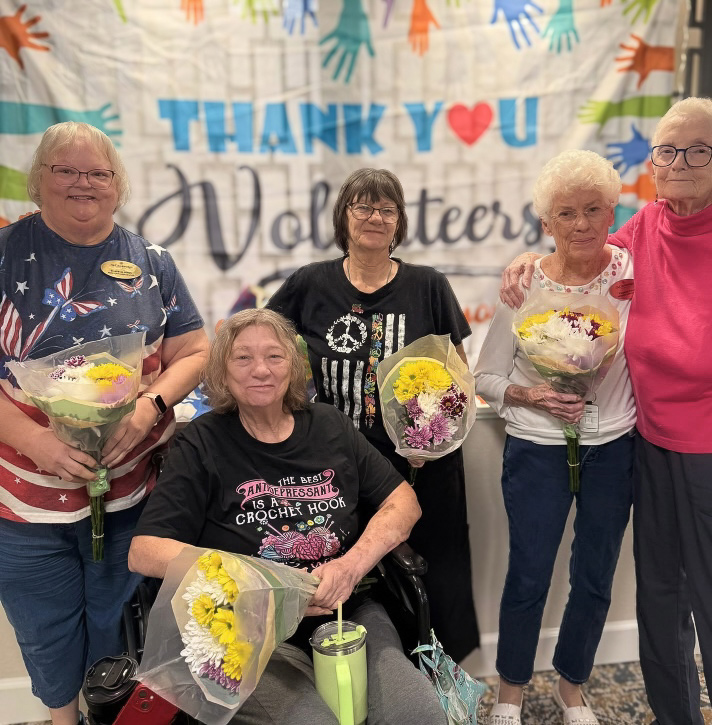 Resident Ambassadors at The Cambridge Senior Living smile, holding bouquets of flowers.